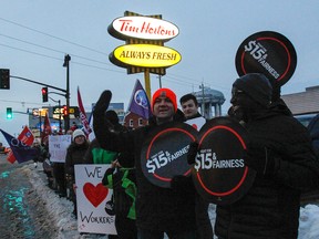 Protesters line the street and sidewalk outside of the Tim Hortons franchise at the corner of Princess and MacDonnell streets in Kingston on Friday as part of a provincewide "day of action" rally to put pressure on the parent company, which has seen some of its franchise owners claw back benefits and paid breaks after the province's minimum hourly wage increase to $14 took effect on Jan. 1. (Julia McKay/The Whig-Standard)