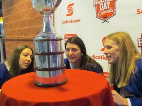 Toronto Furies players, from left, Carolyne Prevost, Alexa Arambura and Jessica Platt, look at names engraved in the Clarkson Cup, the championship trophy in the Canadian Women's Hockey League, during a Scotiabank Hockey Day in Canada event Saturday in Sarnia. (Paul Morden/Sarnia Observer)