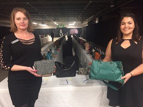Angela Wildfong, left, and Samantha MacKinnon, show off two of hundreds of purses to be auctioned at Handbags for Hospice Friday night. (HEATHER RIVERS, Sentinel-Review)
