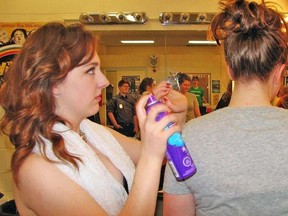 Jack Evans/For The Intelligencer
Rylee Bremner puts a dose of hair spray on one of her fellow actors in last minute back stage preparations for Centennial Seondary’s drama evening, “Retail Therapy.”