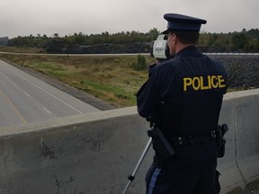An OPP officer uses a radar gun to track speeders on an area highway. (Postmedia file photo)