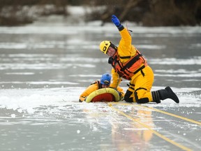 Brian Tapp, of the London fire department?s water-ice rescue team waves for colleague Ron Vermeltfoort to be pulled ashore during ice rescue training Tuesday. (MIKE HENSEN, The London Free Press)