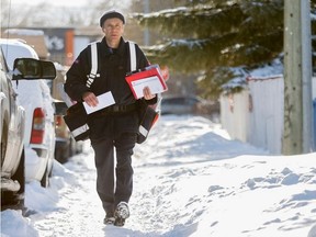 A Canada Post worker delivers mail door-to-door. (Lyle Aspinall/Postmedia)