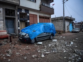 A damaged car is covered with debris of a house which was hit by a rocket in the Turkish border province of Kilis on January 24, 2018. Rockets fired from Syria killed two people and wounded 11 others on January 24 in southern Turkey on the fifth day of Ankara's offensive against a Syrian Kurdish militia which President Recep Tayyip Erdogan vowed to eliminate. (AFP PHOTO)