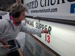 Sign of the times - Cathy Graham puts up notice of forthcoming Shrove Tuesday pancake supper at Port Stanley United Church. (Eric Bunnell/Times-Journal)