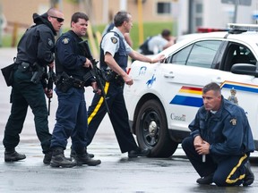 Police keep watch on a house as they search for a heavily armed gunman following the shooting of three Mounties in Moncton, N.B., on June 5, 2014. THE CANADIAN PRESS/Marc Grandmaison