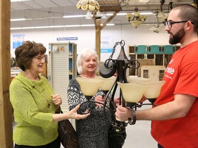 Lance St. Louis, of the Habitat for Humanity Ontario Gateway North ReStore, shows a lighting fixture to his grandmothers, Carmelle St. Louis, left, and Gerry Jones, at  a VIP celebration at the new store at 799 Notre Dame Ave. in Sudbury, Ont. on Friday January 26, 2018. The grand opening was held on Saturday with a ribbon cutting ceremony. John Lappa/Sudbury Star/Postmedia Network