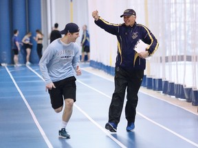 Head coach Dick Moss, right, jokes around wth Liam Pedersen, of Laurentian Voyageurs indoor track team, while training at the indoor track facility at Laurentian University in Sudbury, Ont. on Friday January 26, 2018. John Lappa/Sudbury Star/Postmedia Network