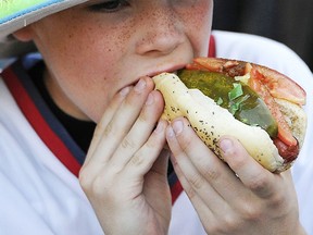Chowing down on a hot dog is a common sight at arenas and stadiums across North America. Unfortunately, usually, teams charge too much for their food. (Associated Press photo)