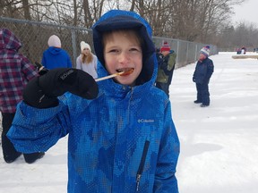 Daniel Power eats maple syrup taffy at Pierre Elliott Trudeau elementary school’s French Carnaval Friday afternoon. The school puts on a French Carnaval every year to help the children learn about French history and culture. (Laura Broadley/Times-Journal)