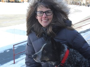 Lindsay Hadcock sits with her dog, Busy, at the Memorial Centre dog park. (Steph Crosier/The Whig-Standard/Postmedia Network)