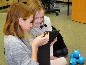 Ally Vogels (left) and Aubrey Vosper look over their coding steps on their iPads while their robot Dash awaits his instructions. ANDY BADER/MITCHELL ADVOCATE
