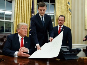 In this Jan. 20, 2017 file photo, White House Staff Secretary Rob Porter, center, hands President Donald Trump a confirmation order for James Mattis as defense secretary, in the Oval Office of the White House in Washington, as White House Chief of Staff Reince Priebus, right, watches. (AP Photo/Evan Vucci)