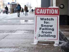 Wellington Street pedestrians are warned to watch for snow falling from Citi Plaza Wednesday as the area braces for more cold and flurries ahead. (DEREK RUTTAN/THE LONDON FREE PRESS)