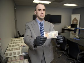 Detective constable Paul Ferreira with counterfeit bank notes recently seized in London, Ont. on Wednesday February 7, 2018. (DEREK RUTTAN, The London Free Press)
