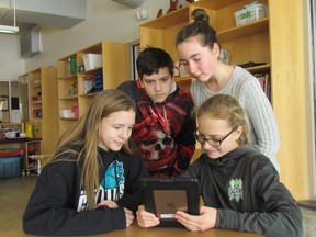 P. E. McGibbon Public School Grade 7 students, seated from left, Tamara Smith, 12, and Clara Veenendaal, 12, and standing from left, Ethan Duarte, 12, and Ella Derkzen, 12, use school-supplied iPads to create weekly video announcements at the Sarnia school. The Lambton Kent District School Board is asking parents and guardians of students in Grades 6 to 10 to take part in a survey on the future of a program providing iPads to students beginning in Grade 7. (Paul Morden/Sarnia Observer)