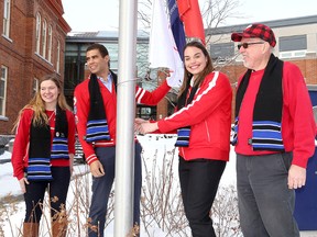 Ian MacAlpine/The Whig-Standard
Parapan Am Games athlete Anne Fergusson, left, and former Olympians Greg Douglas and Christine Robinson, with Smith School of Business dean David Saunders, raise a flag after a  ceremony on Thursday at the school at Queen’s University celebrating the start of the 2018 Olympic Winter Games and the school’s relationship with the Canadian Olympic Committee.