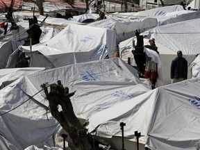 In this photo taken on Thursday, March 16, 2017, a migrant stands between tents at the Moria refugee detention center on the northeastern Greek island of Lesbos. Thanassis Stavrakis / AP