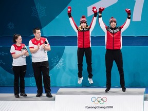 Canadians Kaitlyn Lawes, centre, and John Morris, right, react after winning gold as Switzerland teammates Jenny Perret, left, and Martin Rios, second left, look on during mixed doubles curling medal ceremony at the 2018 Olympic Winter Games in Gangneung, South Korea on Tuesday, February 13, 2018. THE CANADIAN PRESS/Nathan Denette
