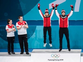 Canadians Kaitlyn Lawes, centre, and John Morris, right, react after winning gold as Switzerland teammates Jenny Perret, left, and Martin Rios, second left, look on during mixed doubles curling medal ceremony at the 2018 Olympic Winter Games in Gangneung, South Korea on Tuesday. THE CANADIAN PRESS/Nathan Denette