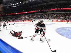 Latvia's Kirils Tambijevs, left, and Canada's Eric O'Dell fight for the puck during an exhibition hockey game in Riga, Latvia, Sunday, Feb. 4, 2018. (AP Photo/Roman Koksarov)