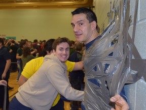 Grade 12 student Max MacGillivray tapes Gino Posteraro to the gym wall at St. Benedict in support of the Northern Ontario Families of Children with Cancer. Supplied photo
