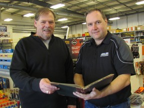 Sales manager Albert Hoekstra, left, and manager and co-owner Greg Primmer, hold a 1900-era corporate minutes book at Mackenzie Milne, a Sarnia business celebrating its 170th anniversary. (Paul Morden/Sarnia Observer/Postmedia Network)