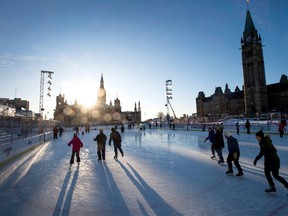People skate on the Canada 150 Skating Rink as the sun begins to set behind West Block on Parliament Hill in Ottawa on Monday, Feb. 12, 2018. (The Canadian Press)