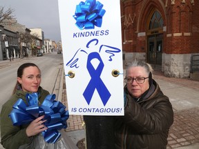 Jennifer Rosatte (left)  and Chris Macdonald post signals of kindness outside city hall Sunday morning