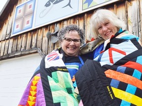 Denise Corneil, left, and Mary Simpson stand outside Corneil's house in Wardsville, in southwestern Middlesex County. They're draped in a collage of barn quilts, designs they picked out for a little project to commemorate Wardsville's bicentennial in 2010. A similar Barn Quilt Trail is being developed in Dawn-Euphemia Township and the Dresden area, it was announced this week. (File photo)