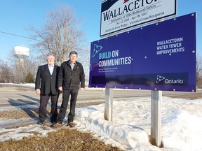 Dutton Dunwich councillor Dan McKillop, left, and Mayor Cameron McWilliam stand beside a Wallacetown water tower project sign. The tower, visible in the background, is undergoing a $448,880 rechlorination system upgrade covered through provincial grants and municipal funds. Vicki Gough/Special to Postmedia News