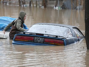 Chatham-Kent has declared a state of emergency as the Thames River was expected to peak near Thamesville on Friday. Here, Amber Hawkins checks out a car parked in the rear of a downtown Chatham home near the river. Dan Janisse/Postmedia Network