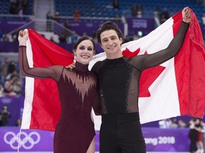 Ice dance gold medallists Canada's Tessa Virtue and Scott Moir hold up the Canadian flag during victory ceremonies at the Pyeongchang Winter Olympics. (THE CANADIAN PRESS)