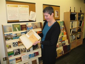 Jack Evans/For The Intelligencer
Archivist Amanda Hill studies the minute book of the former Belleville Presto Club in front of a stand of other typical archive items.