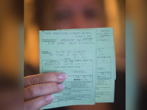 A woman holds two citations totalling $2,260 in fines she received after driving patients to the hospital in London. (DEREK RUTTAN, The London Free Press)