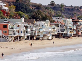 In this Dec. 20, 2015, file photo, waves roll up to and under homes perched over a sandy beach in Malibu, Calif. (AP Photo/John Antczak, file)