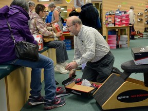 Jeff Seigel, above, helps a customer with shoes Thursday at J. Seigel Footwear Inc. Seigel, the third generation of his family to sell shoes in London, is retiring, news that caused lineups of customers outside the store on Highbury Avenue. (MORRIS LAMONT, The London Free Press)