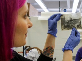 Colette Hardman-Peavy, left, a second-year masters Art Conservation (paper and new media) student takes a closer look at the deterioration of the emulsion in an old photograph. The Art Conservation masters program at Queen's University announced receiving a $632,000, five-year grant from the Andrew W. Mellon Foundation in one of the programs labs at the university in Kingston on Thursday. Julia McKay/The Whig-Standard/Postmedia Network