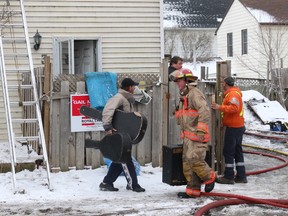 Belleville firefighters help a man retrieve some belongings from a home on Emily Street, near Station Street, after an early-morning fire gutted the home on Friday. Firefighters arrived on scene at 6:30 a.m. and woke the lone occupant who was able to escape without injury. The cause remains under investigation and no cause has been determined.