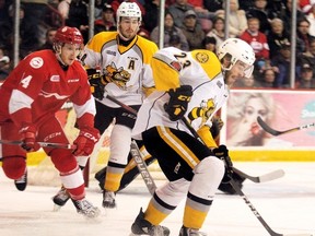 Sarnia Sting's Curtis Egert (23) carries the puck while teammate Connor Schlichting and Soo Greyhounds' Taylor Raddysh look on during the first period Friday at the Essar Centre in Sault Ste. Marie, Ont. BRIAN KELLY/Postmedia Network