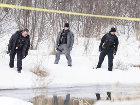 Members of the Greater Sudbury Police Service, including forensic identification specialist Ryan McMahon, left, gather evidence on the bank of Lily Creek at Beverly Drive, off Martindale Road, where a deceased man was found on Monday. (Gino Donato/Sudbury Star)