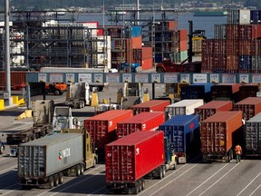A man walks between transport trucks waiting to deliver cargo at Port Metro Vancouver's Center container facility in a May 10, 2013 file photo. (THE CANADIAN PRESS/Darryl Dyck)