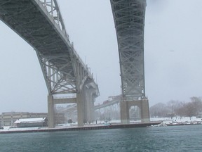 The two spans of the Blue Water Bridge are shown from the shore of the St. Clair River in Point Edward. Operators on both sides of the international crossing recently adjusted the exchange rate for tolls. (Paul Morden/Sarnia Observer/Postmedia Network)