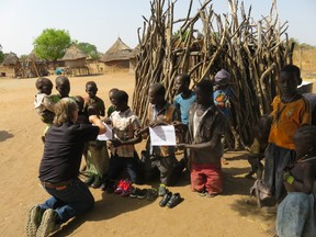 In the countryside near Jebel Lado, Thorndale farmer and volunteer Stuart McCutcheon offers gifts to South Sudanese children. (Supplied)