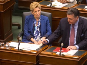 Provincial Finance Minister Charles Sousa, right, passes a note to Ontario Premier Kathleen Wynne during the Throne Speech at the Ontario Legislature in Toronto on Monday, March 19, 2018. THE CANADIAN PRESS/Chris Young
