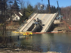 Workers start the process of removing a dump truck from the collapsed Port Bruce bridge on Monday. Its removal was delayed.