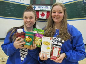 Izzy Kokkinis, 17, and Beth Schoenmaker, 18, co-chairpersons of the St. Patrick's Catholic High School Cyclone Aid food drive, hold up examples of food items hundreds of the Sarnia school's students and other volunteers are expecting to collect on Saturday. The annual student food drive visits neighbourhoods around the city to collect donations for the Inn of the Good Shepherd food bank. (Paul Morden/Sarnia Observer/Postmedia Network)