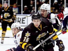 Sarnia Sting's Jordan Ernst (16) skates away from an attempted check by Windsor Spitfires' Tyler Angle, left, and Thomas Stevenson at Progressive Auto Sales Arena in Sarnia, Ont., on Friday, Jan. 12, 2018. (Mark Malone/Postmedia Network)