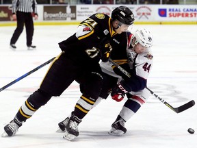 Sarnia Sting's Adam Ruzicka (21) and Windsor Spitfires' Nathan Staios (44) battle for the puck in the first period during Game 1 in their OHL Western Conference quarter-final at Progressive Auto Sales Arena in Sarnia, Ont., on Friday, March 23, 2018. (Mark Malone/Postmedia Network)