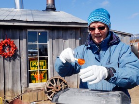 Liz Galbraith makes maple candy over a block of ice Saturday at Nyman Farms east of Demorestville. It was a busy stop on the 17th-annual Maple in the County tour.